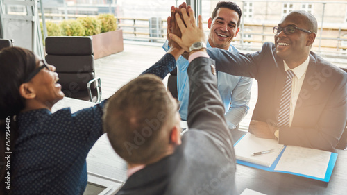 Group of happy successful business people smiling and high fiving each other during a meeting in an office. Businessmen and women showing teamwork, collaboration in a diverse workplace.