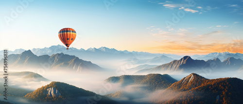 A hot air balloon is flying over foggy mountains high.