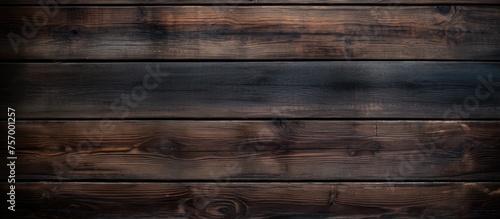 A close up of a brown hardwood plank wall with a wood stain finish, showcasing a beautiful wood grain pattern. The blurred background adds depth to the image