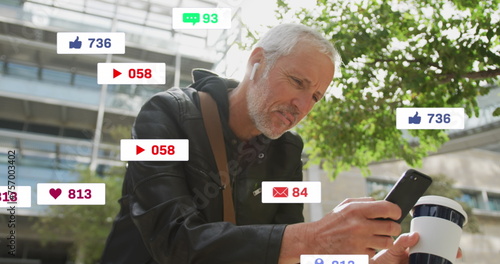 Image of social media icons over senior man using smartphone