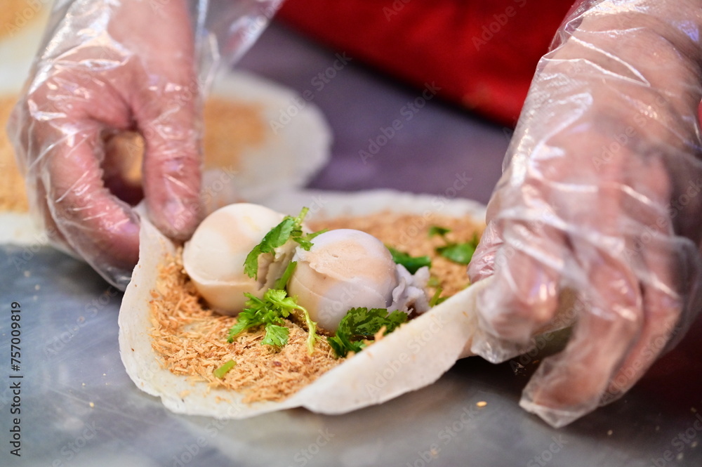 A vendor at the Ningxia Night Market in Taipei, Taiwan, assembles a peanut roll ice cream. The popular Taiwanese snack consists of a crepe, two scoops of ice cream, peanut brittle and coriander.