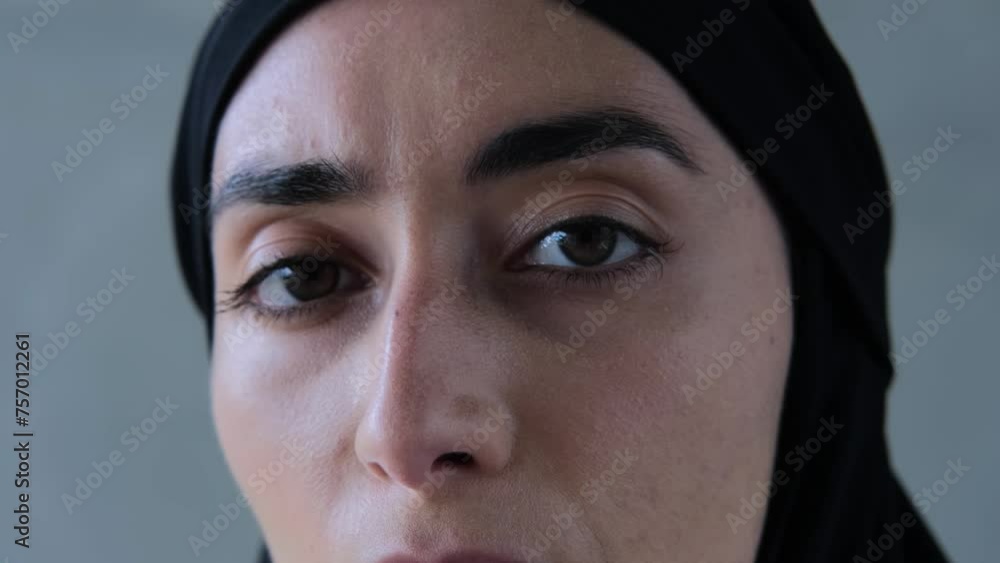 Face of Muslim woman in black hijab in profile, turns and looks at camera. Close-up: thoughtful face of Muslim woman, eyes wide open. Concept: Muslim woman face with reproachful look Face of Muslim woman in black hijab in profile, turns and looks at camera. Close-up: thoughtful face of Muslim woman, eyes wide open. Concept: Muslim woman face with reproachful look