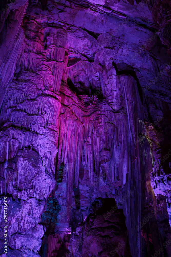Interior of a cave with purple and pinkish illuminated rock walls.