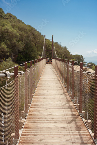 people crossing a suspension bridge in a mountain 