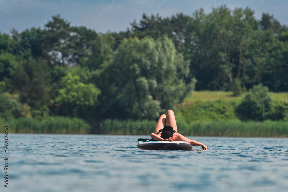 woman in swimming suit sunbathing on supboard