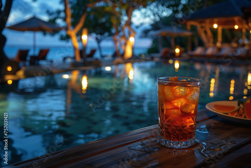 Iced drink on a poolside wooden table during a tropical evening