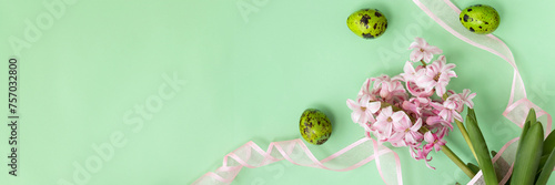 banner of green quail eggs and pink hyacinth flowers, with pink ribbon on pastel green colors. Happy Easter concept. Easter background. Top view. copy space
