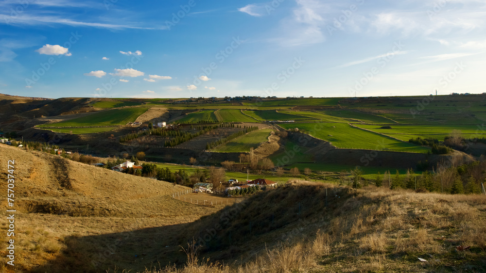 Hills and fields in the countryside. Village settlement and green fields in spring. Blue sky, green fields and dry grass. Hills and fields in the countryside. Village settlement and green fields in spring. Blue sky, green fields and dry grass.