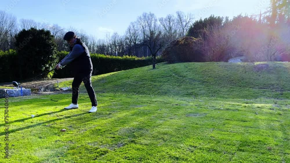 Tracking Shot on an Elegant Male Golfer Making a Practice Golf Swing on the Tee Box with Sunlight and Lens Flare on Golf Course in Switzerland. Tracking Shot on an Elegant Male Golfer Making a Practice Golf Swing on the Tee Box with Sunlight and Lens Flare on Golf Course in Switzerland.