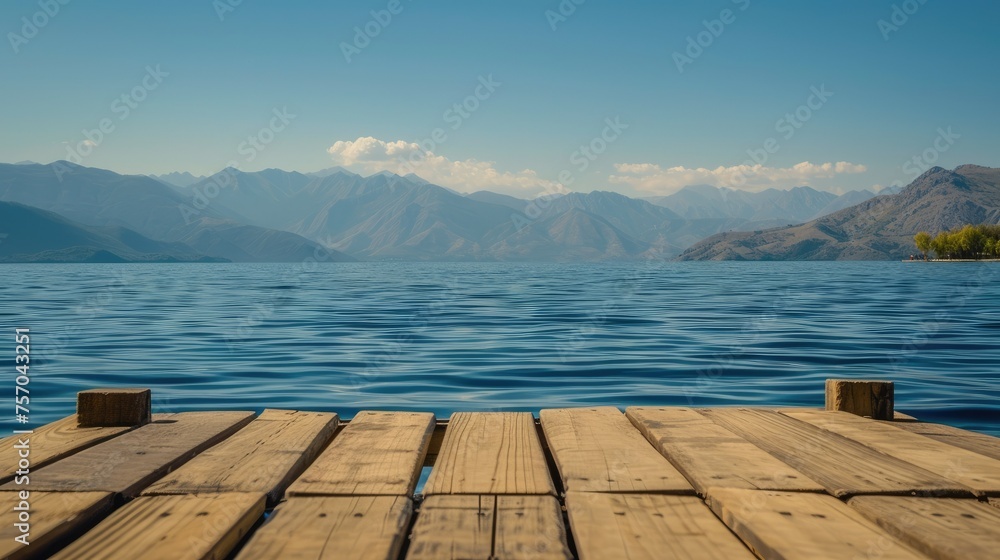 A wooden dock overlooks a large body of water with mountains in the background