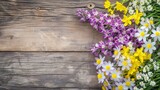 A wooden background with a variety of flowers including yellow and purple