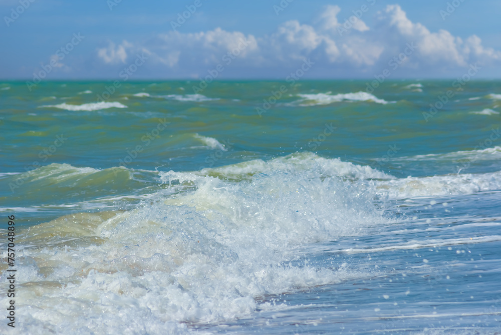 closeup sandy sea beach with waves under cloudy sky
