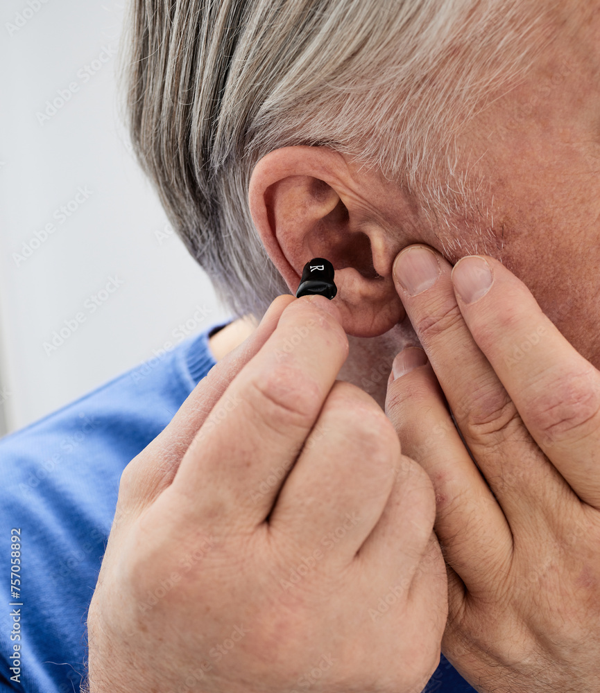 Fototapeta premium Hearing aid in the ear of elderly man, close-up. ITC hearing aid for hear treatment