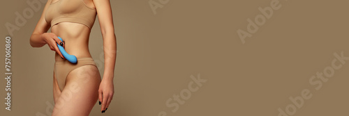 Cropped image of woman in underwear holding vibrator against beige background. Concept of female health care, toys for adults, sexuality, passion and pleasure. Banner. Empty space to insert text, ad