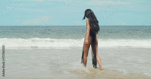 Dressed in an anime cosplay bikini, a girl finds joy on the white sand beach of Trinidad, a Caribbean island with ocean waves in the background photo