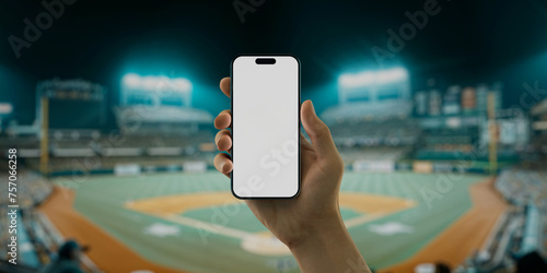 A hand holds a smartphone with a green screen at a baseball stadium photo