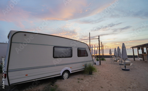 The motorhome is camped out on the sandy beach by the sea in the morning.