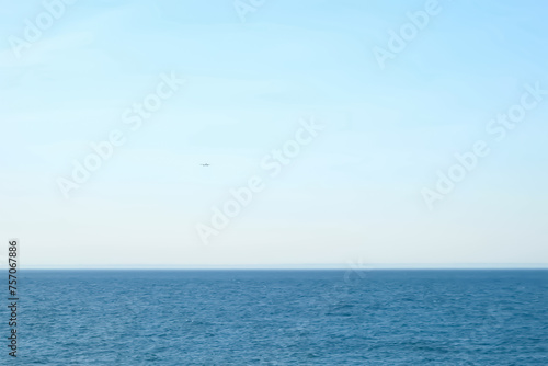 Airplane plane flying over the sea in clear blue sky at sunny weather. Passenger jet approaching to land at airport. Tourism, travel, journey, wanderlust concept, air flight. Calm blue sea on summer. © familylifestyle