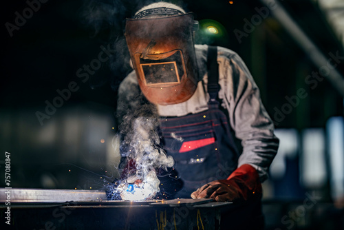 A heavy industry worker is welding at metallurgy factory.