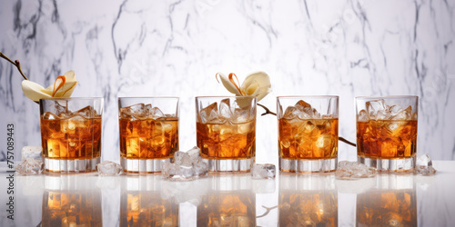 Row of glasses of whiskey or bourbon with ice and flowers on a white marble background. Spring advertising banner of alcoholic beverages mockup.