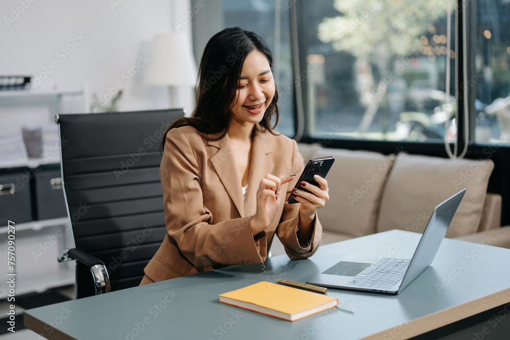 Young beautiful woman using laptop and tablet while sitting at her working place. Concentrated at work. Young beautiful woman using laptop and tablet while sitting at her working place. Concentrated at work.