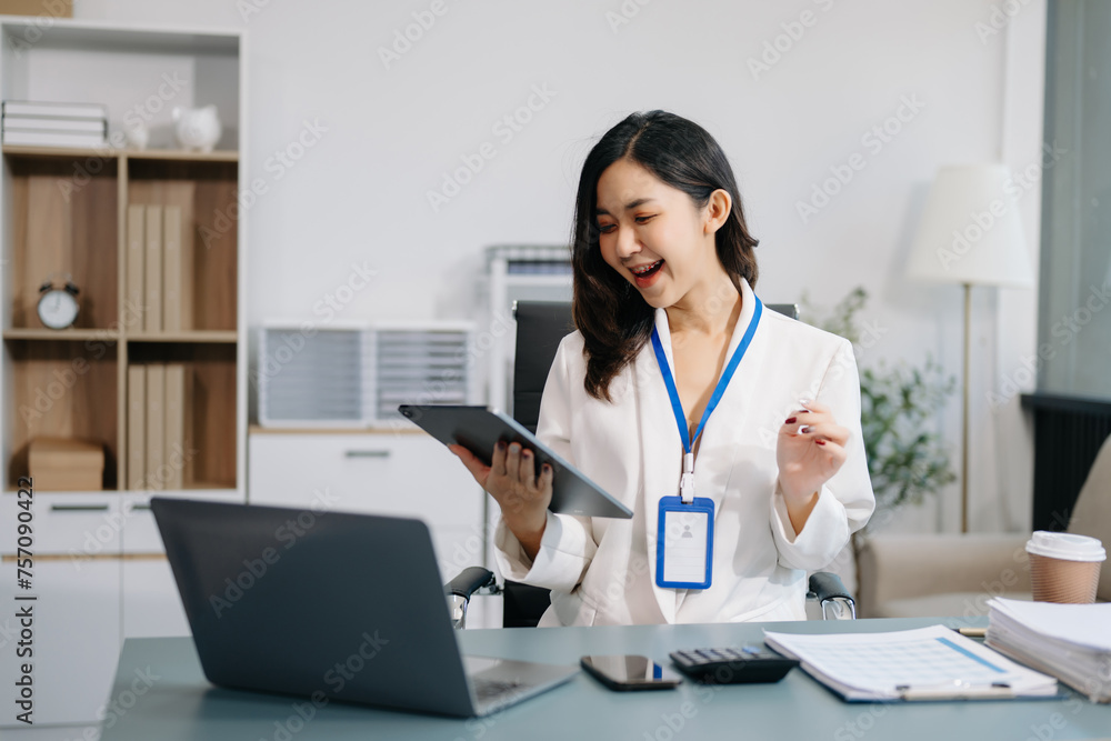 Young beautiful woman using laptop and tablet while sitting at her working place. Concentrated at work. Young beautiful woman using laptop and tablet while sitting at her working place. Concentrated at work.