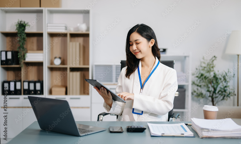 Young beautiful woman using laptop and tablet while sitting at her working place. Concentrated at work. Young beautiful woman using laptop and tablet while sitting at her working place. Concentrated at work.