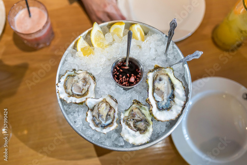 A plate with oysters on ice, a still life with lemon stands on the table in a restaurant