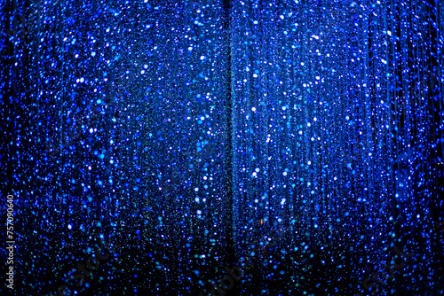 Celebration lights at Christmas New Year festival. Crowd of hanging blue light bulbs blue bokeh background. blue light bulb tunnel. 