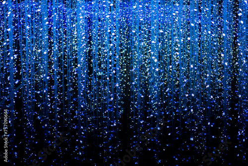 Celebration lights at Christmas New Year festival. Crowd of hanging blue light bulbs blue bokeh background. blue light bulb tunnel. 