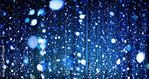 Celebration lights at Christmas New Year festival. Crowd of hanging blue light bulbs blue bokeh background. blue light bulb tunnel. 