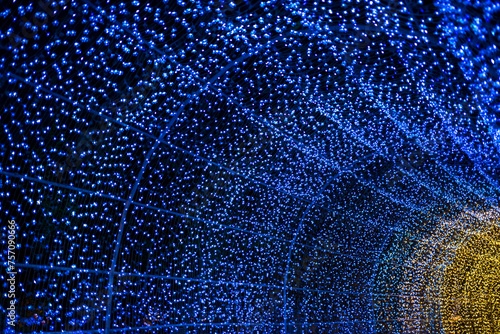Celebration lights at Christmas New Year festival. Crowd of hanging blue light bulbs blue bokeh background. blue light bulb tunnel. 