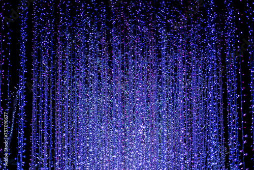 Celebration lights at Christmas New Year festival. Crowd of hanging blue light bulbs blue bokeh background. blue light bulb tunnel. 