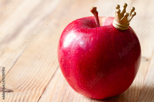 Apple with crown on wooden background, king of fruits concept abstract