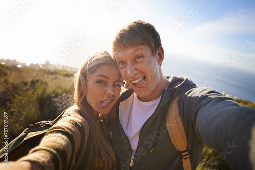 Funny, face and hiking couple with selfie in nature for bonding, fun or goofy memory at sunset. Happy, love and people embrace for silly profile picture, photography or social media travel blog photo © peopleimages.com