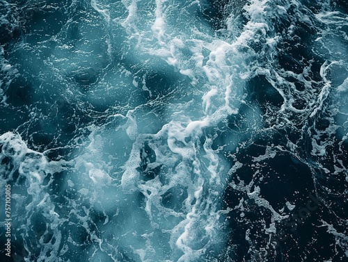 Aerial view of dark blue ocean water with white frothy waves creating a dynamic texture.