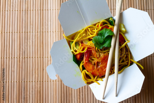 Chinese noodles with shrimps and vegetables in box on bamboo mat. Chinese food concept