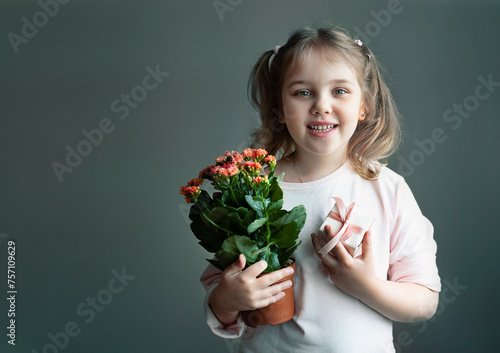 caucasian child girl holding pot with plant and gift box, little kid portrait empty copy space holiday design, female with greeting presents.Teacher's day, mother's day.