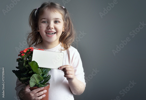 Child girl holding paper empty space card portrait. Little kid with flower pot showing informatrion poster. Mother's day,holiday greetings.