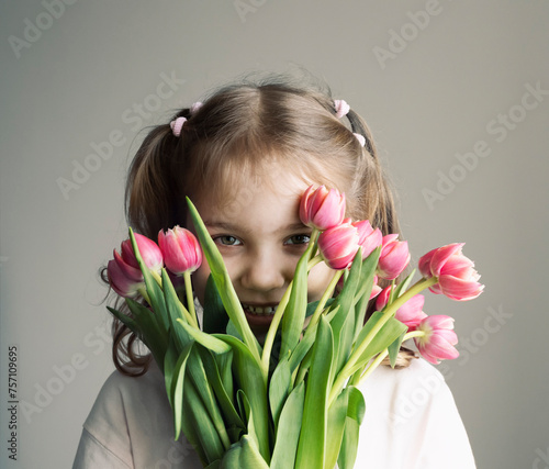Caucasian child girl holding bouquet of tulips,spring season. Kid portrait with flowers.Mother's day.