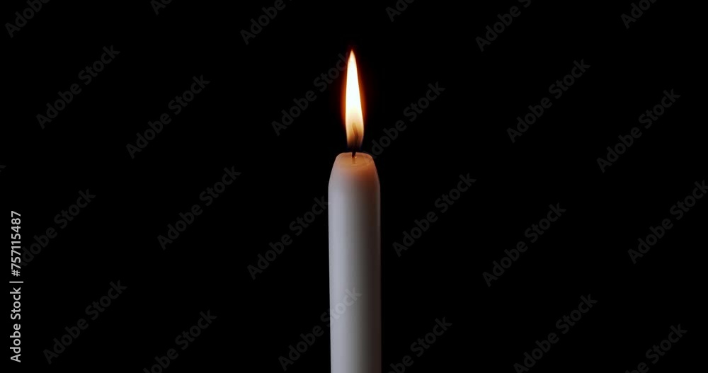 A single white candle burning. Isolated candle slow motion burning with dark background. White paraffin candle with yellow shades burns on a black background. Slow motion. A single white candle burning. Isolated candle slow motion burning with dark background. White paraffin candle with yellow shades burns on a black background. Slow motion.