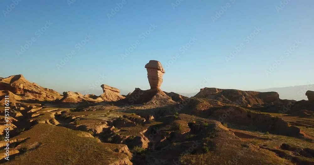 Fly over a single alone pillar wind erosion rock cliff geology erosion in desert climate in Iran natural wonderful scenic landscape in summer sunset time blue sky and wild nature road trip in Iran