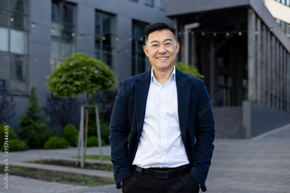 Confident businessman smiling outside modern office building Confident businessman smiling outside modern office building