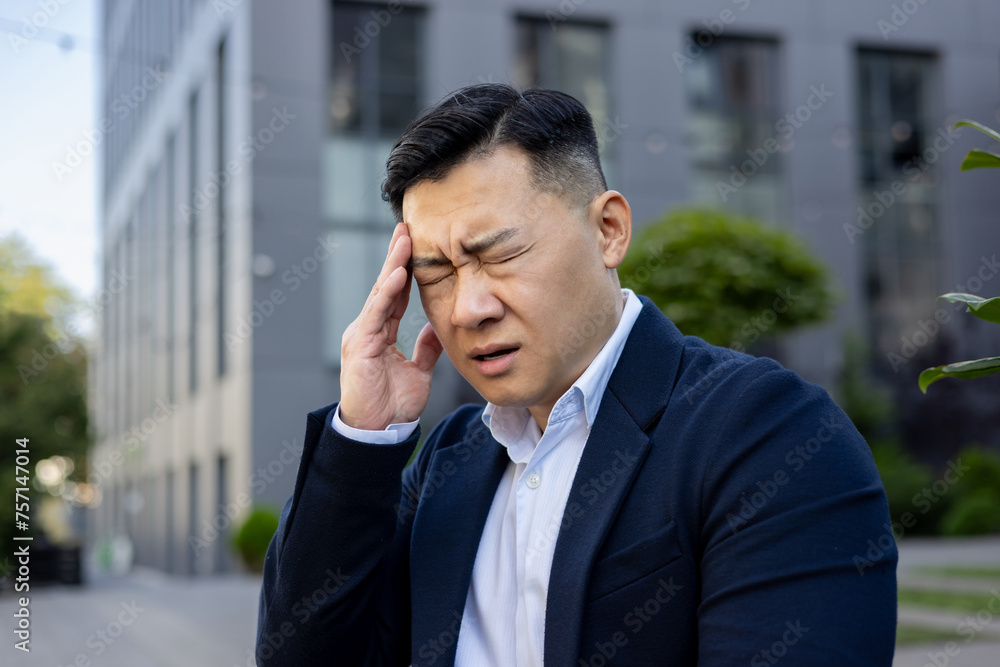 Stressed businessman with headache standing outdoors Stressed businessman with headache standing outdoors