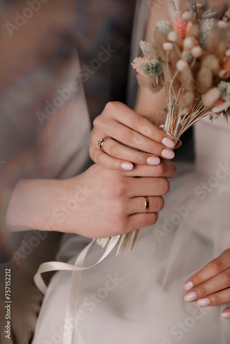 the hands of a man and a woman with gold wedding rings hold onto a wedding bouquet of dried flowersthe hands of a man and a woman with gold wedding rings hold onto a wedding bouquet of dried flowers photo