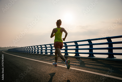 Fitness woman runner running on seaside bridge