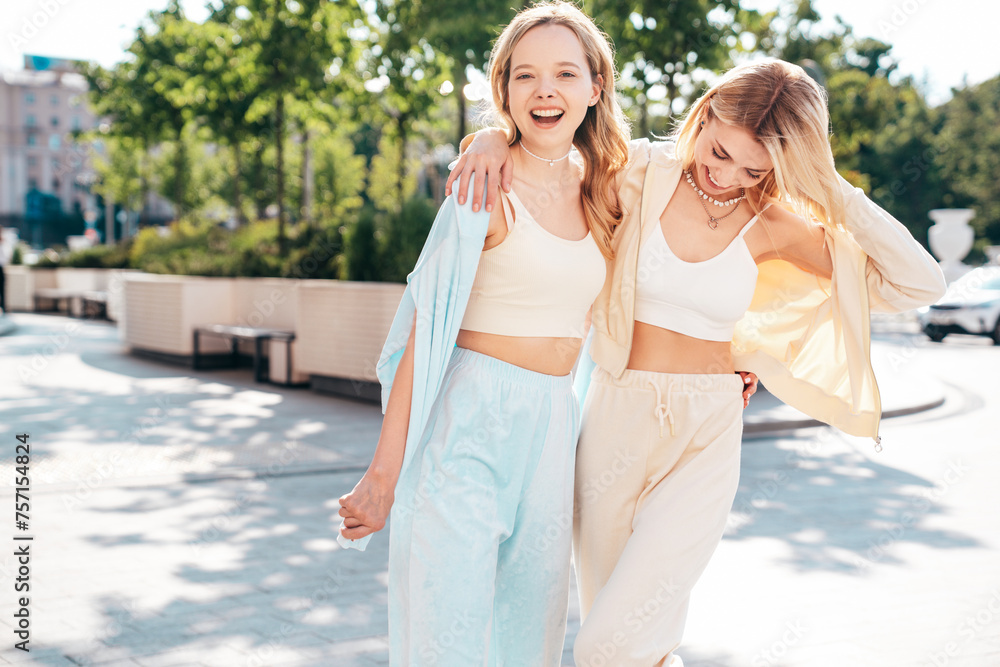 Two young beautiful smiling hipster female in trendy summer clothes. Sexy carefree women posing on street background. Positive models having fun, hugging at sunset