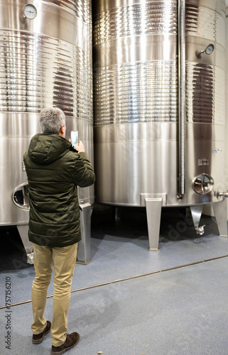 Winemaker inspecting stainless steel fermentation tanks, copy space. photo