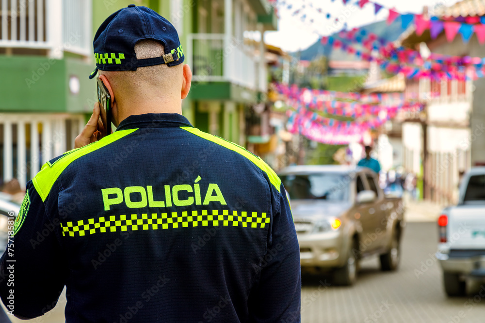 Colombian police officer seen from behind while talking on the phone Colombian police officer seen from behind while talking on the phone
