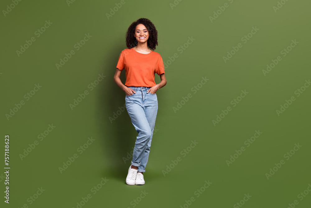 Full length photo of adorable cheerful lady dressed orange t-shirt smiling empty space isolated khaki color background Full length photo of adorable cheerful lady dressed orange t-shirt smiling empty space isolated khaki color background